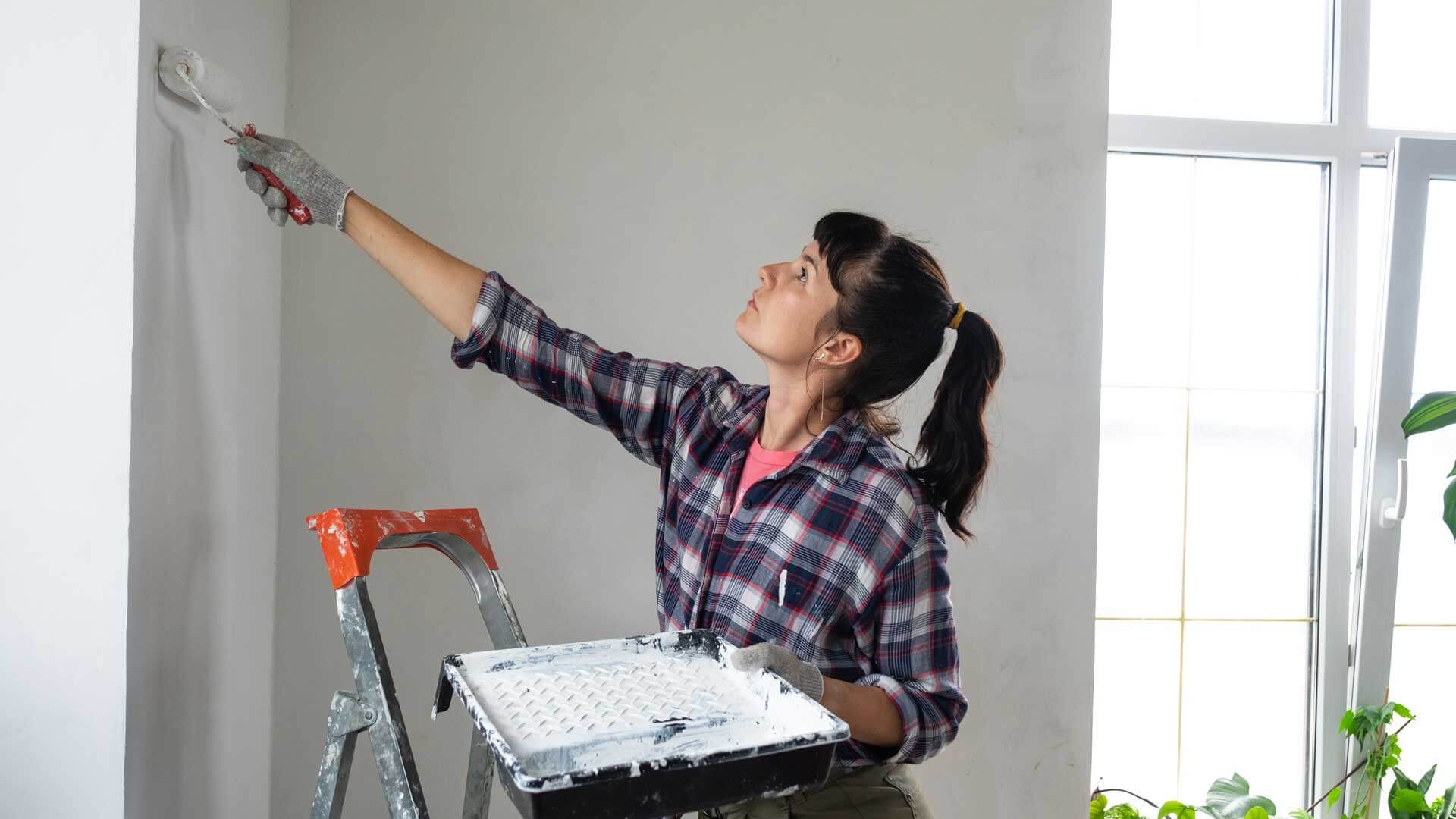 Woman painting a wall, avoiding lead exposure to lead paint.