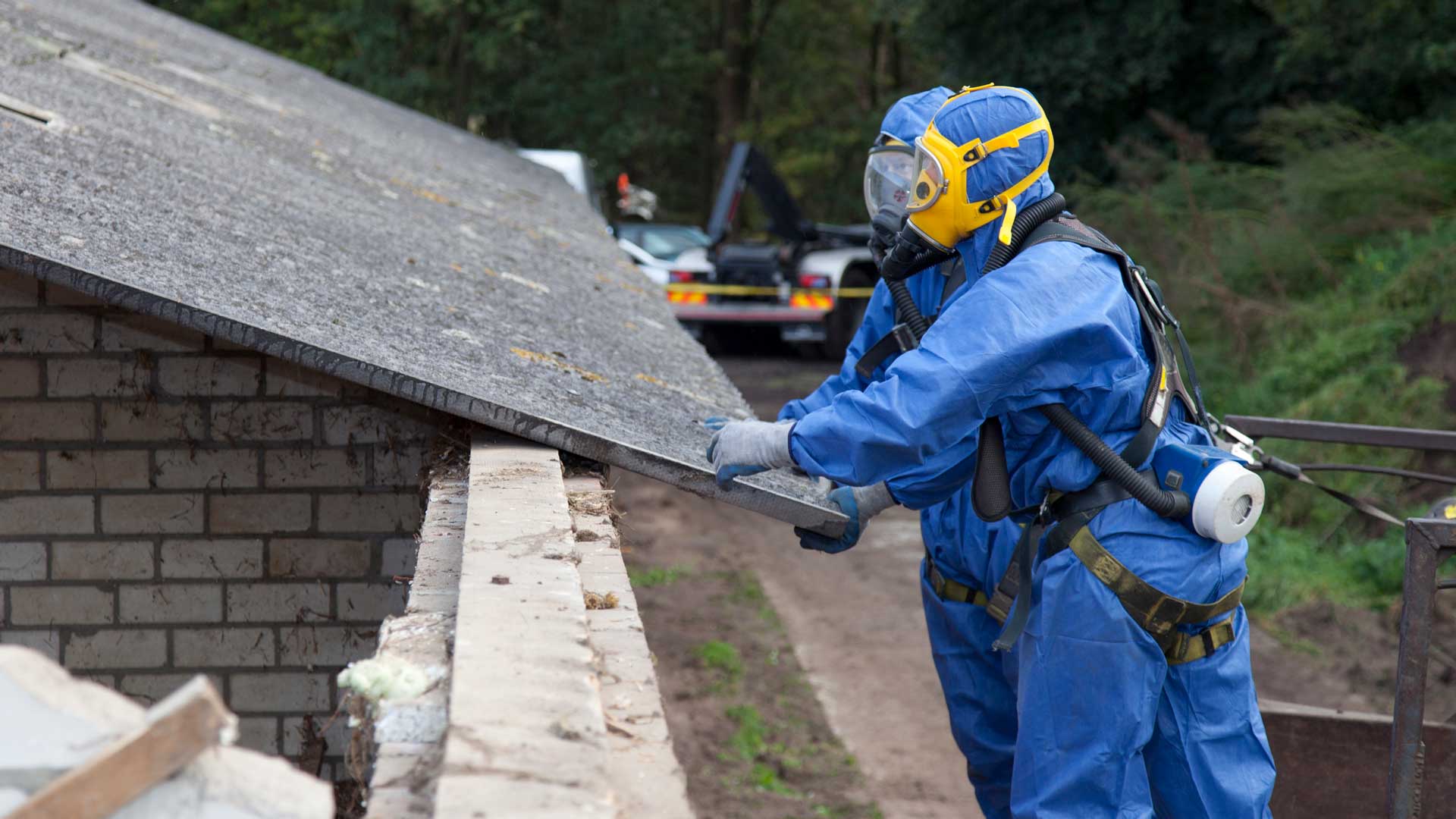 Two professionals dressed head-to-toe in abestos protection suits.