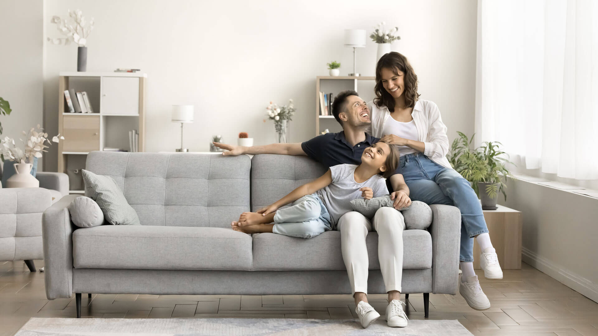 Family of three sitting on a gray couch discussing Actalent's Employee Assistance Program (EAP).