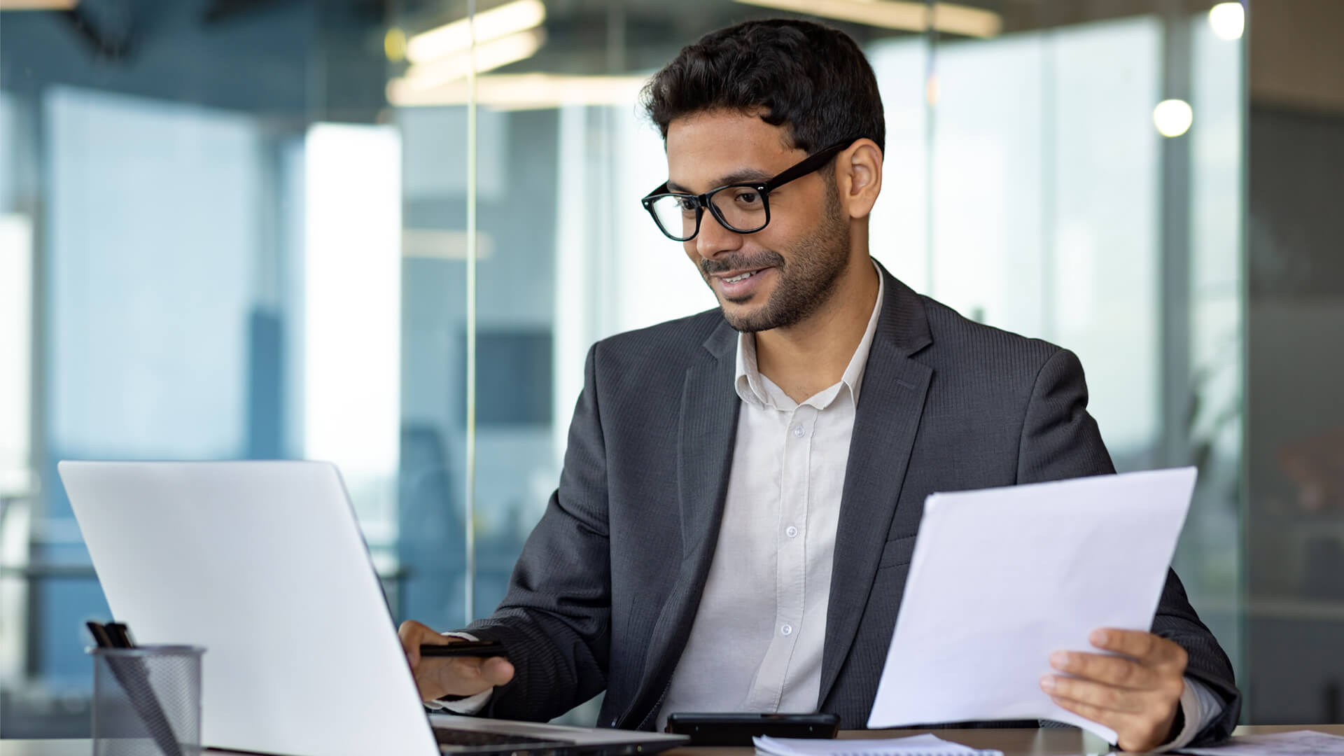 man wearing glasses happily reading Actalent's latest economy and labor market report for January 2025