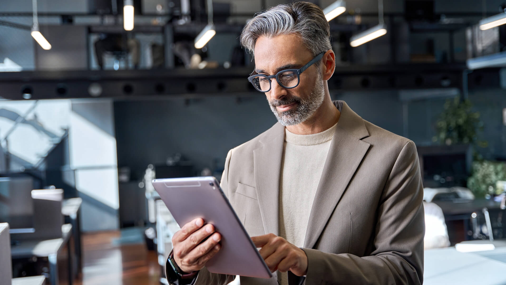 Male wearing glasses reviewing the Q3 2024 Canada labour report, looking at economy trends, on his iPad.