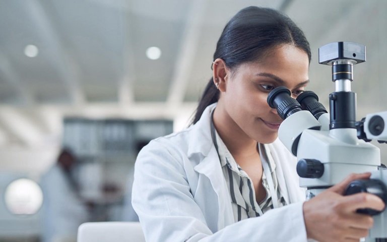 young female scientist using a microscope while conducting research in a laboratory